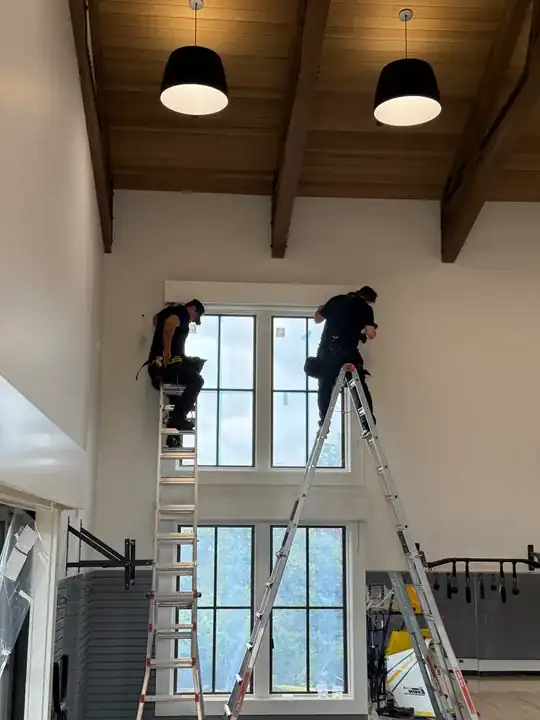 Alro installers fitting window coverings in a tall room
