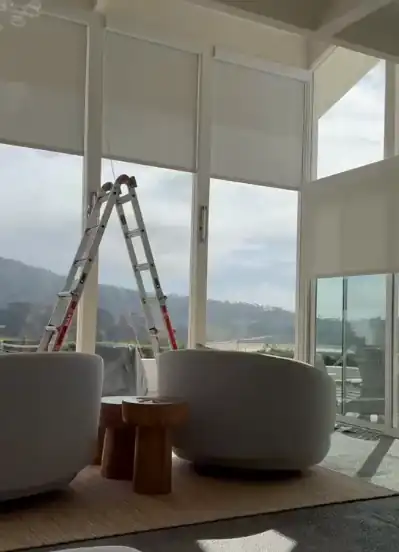 Window treatment installation in a bright room with mountain views