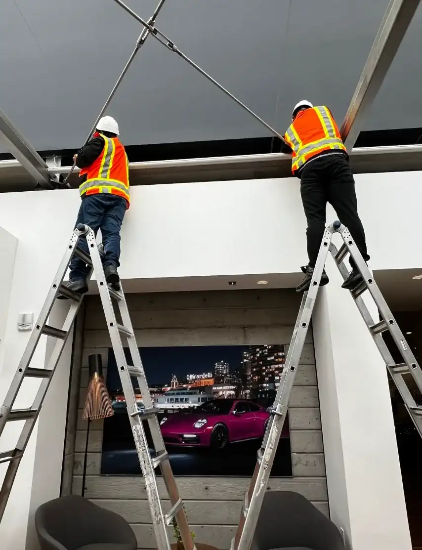 Two Alro installers fitting window coverings beneath a skylight