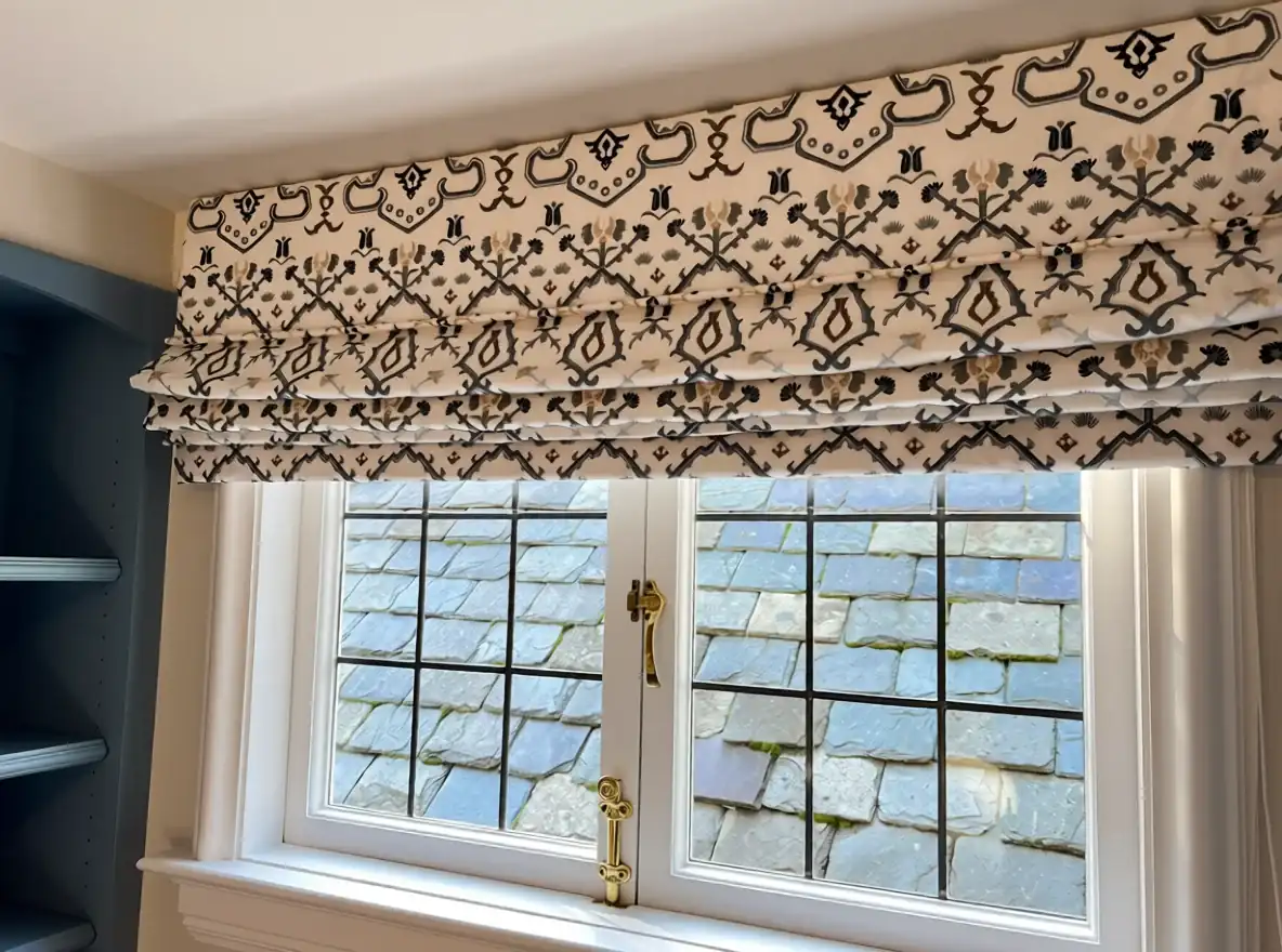 Patterned Roman shade installed above a double window
